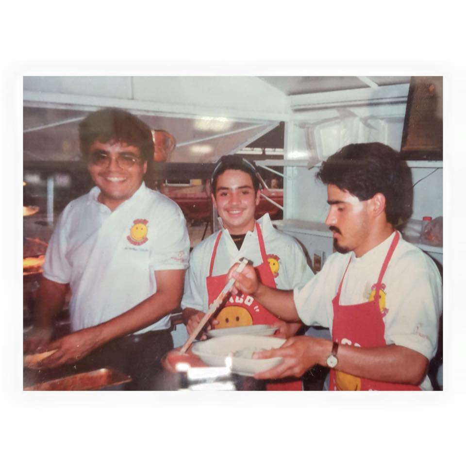 The Chago family kitchen in the early years — aprons with the original smiley mascot